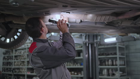 The-mechanic-inspects-the-exhaust-system-of-the-car-in-the-car-service